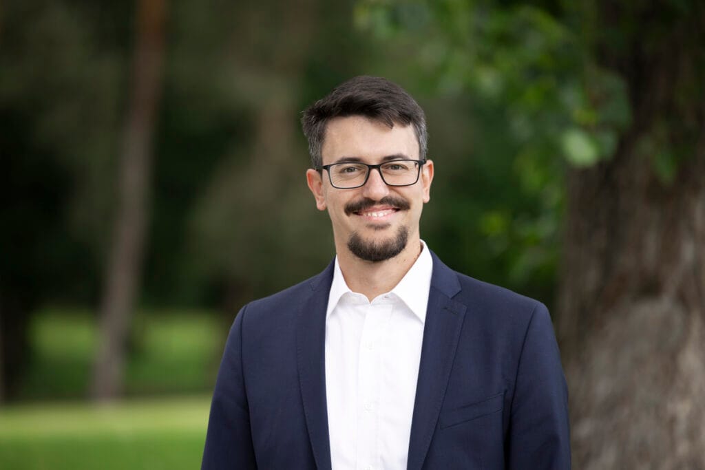 Über uns 3 Micha Wiegel im Anzug im Freien, Sustainable Finance Analyst